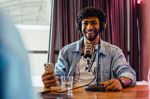 Cheerful podcast host engaged in a conversation with a guest while recording a show in a studio