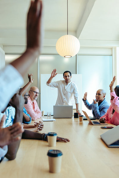 Business meeting with diverse team raising hands to vote on a decision with a divided opinion