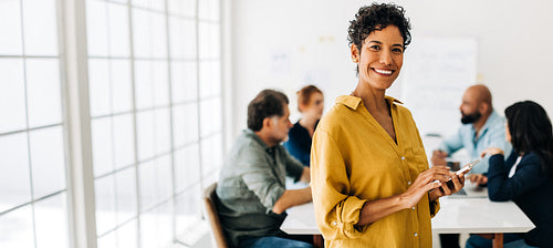 Professional black woman holding a smart phone in an office