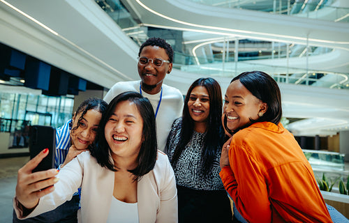 Enthusiastic coworkers take a group selfie in a state-of-the-art office space