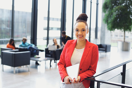 Pretty young businesswoman in office with laptop in hand
