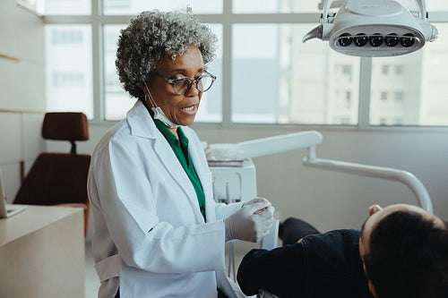 Dentist consulting senior patient during dental checkup in a modern clinic