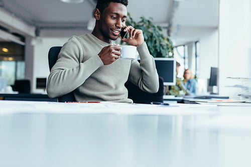 African man talking on mobile phone and drinking coffee