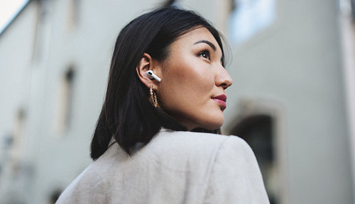 Business woman listening to music with earphones in the city