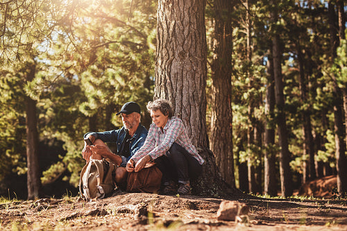 Mature couple under a tree with backpacks and compass