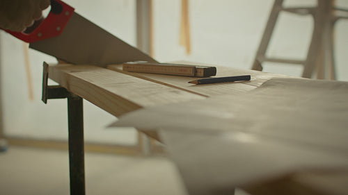 Man sawing wood plank during home renovation