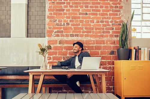 Happy young man sitting at a cafe with laptop