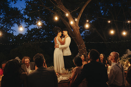 Romantic nighttime intimate wedding celebration in a backyard garden under string lights