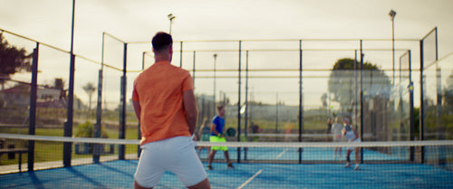 People enjoying an energetic game of padel on a bright outdoor court