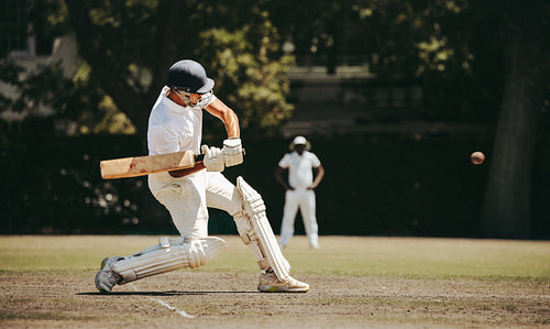 Batsman striking a cricket ball during a match on a sunny day