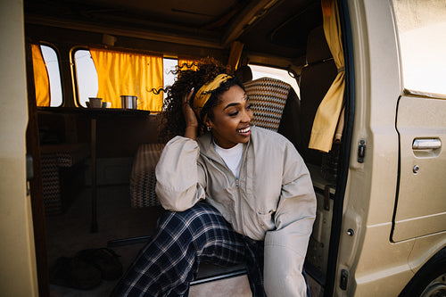A joyful woman sits in a cozy camper van smiling during a relaxed road trip