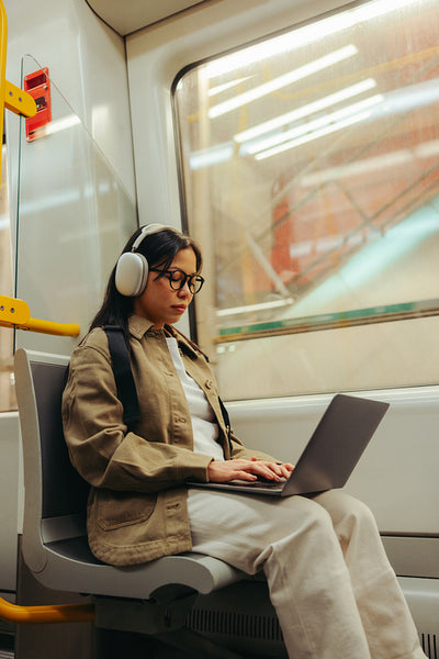 Commuter with laptop and headphones working on a subway train
