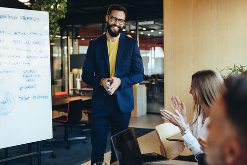 Successful businessman receiving an applause from his team