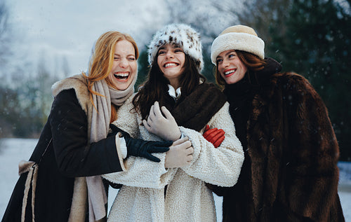Friends and women laugh together on a snowy winter day