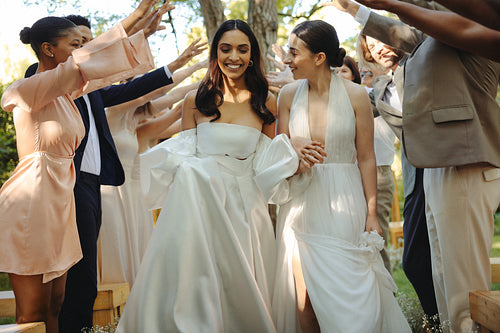 Lesbian couple exits wedding ceremony surrounded by supportive friends