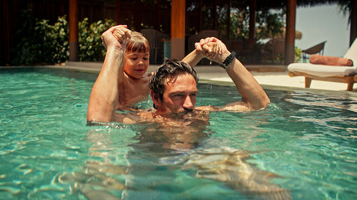 Father and son playing in pool at tropical villa resort