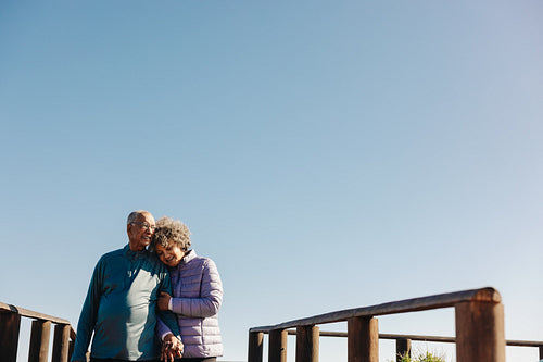 Loving senior couple taking a walk along a bridge at the beach