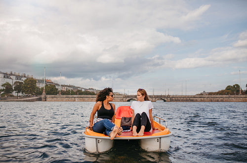 Two young women friends sitting in front pedal boat