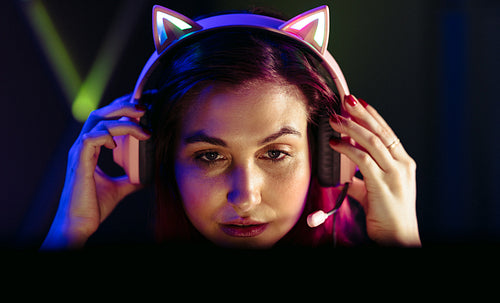 Concentrating on the game, woman adjusts her gaming headset