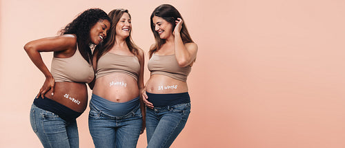 Happy multicultural mothers celebrating the third trimester of pregnancy in a studio