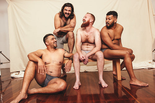 Group of shirtless men laughing and having fun in a studio