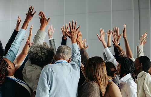 Hands raised by diverse professionals during an engaging business workshop, showcasing teamwork and active participation in a collaborative environment