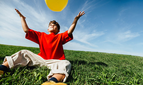 Boy enjoying playful ball game in sunny open field