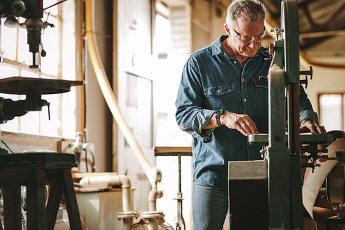 Mature male carpenter working on band saw