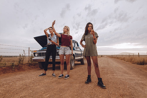 Woman with broken down car in middle of road trip