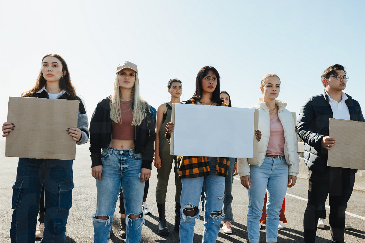 Group of young activists holding blank signs during an outdoor protest ...