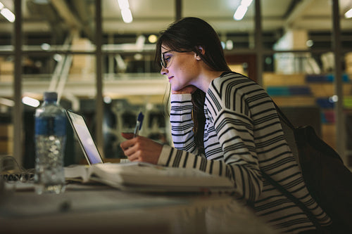 Woman student doing assignment in college library