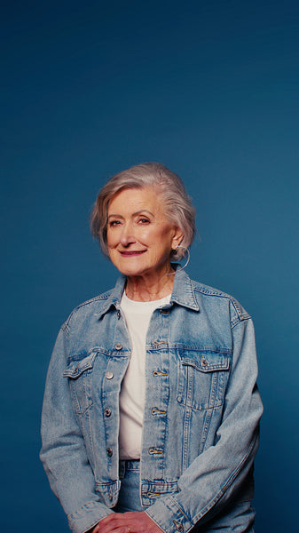 Portrait of a happy senior woman in a denim jacket on a blue background