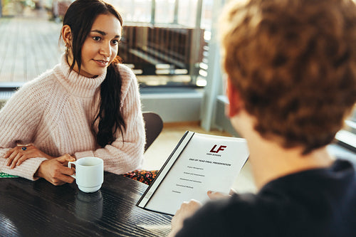 Student showing project file to classmate in college