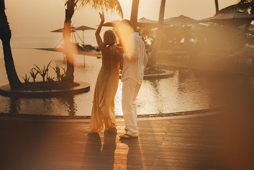 Silhouette of a couple dancing poolside at sunset in a luxurious holiday resort