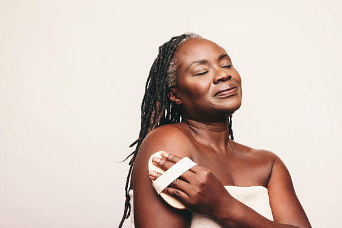 Woman exfoliating her skin with a dry brush