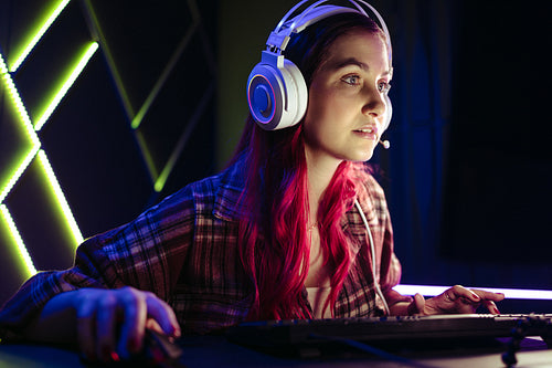 Gaming girl focusing on her computer screen as she takes on an online video game
