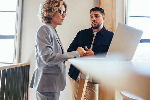 Two business people talking to each other about a project in an office