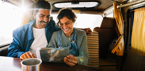 Couple traveling in camper van reviewing map and planning a road trip together