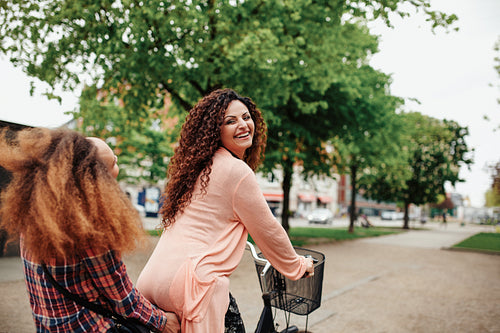 Beautiful woman riding bicycle with her friend