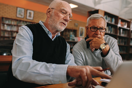 Senior men discussing subject sitting in a library