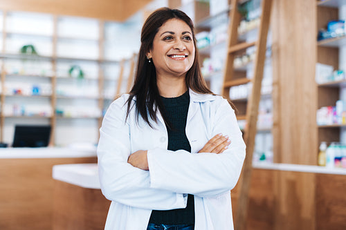 Female pharmacist standing in a chemist with crossed arms