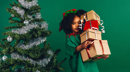 Kid in christmas costume holding gift boxes