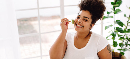 Pretty woman using massage roller on facial skin
