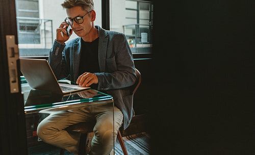 Entrepreneur discussing work over mobile phone at his desk