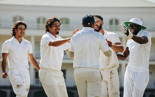 Cricket players celebrating a victory outdoors in a sports team setting