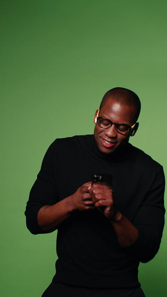 Man in black turtleneck dancing to music on his smartphone with wireless earphones