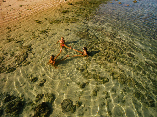 Aerial view of three young women sitting in sea