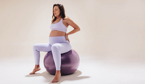 Pregnant woman practicing prenatal yoga on exercise ball for maternal health and wellness