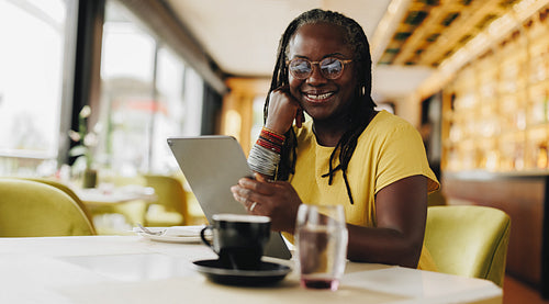Happy mature woman working with a digital tablet in a cafe