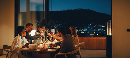 Friends having dinner together at home with scenic night view